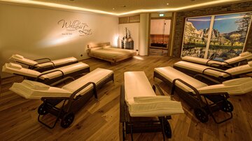 A relaxing wellness room with loungers and a warm wooden floor. Gentle lighting and decorative elements create a calm atmosphere.