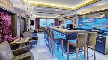 Eine elegante Bar mit bequemen Stühlen und moderner Beleuchtung. Der Raum hat eine einladende Atmosphäre und stilvolle Dekoration.