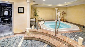 Ein eleganter Wellnessbereich mit einem Whirlpool und einer stilvollen Steinverkleidung. Sanfte Beleuchtung und dekorative Elemente schaffen eine entspannende Atmosphäre.