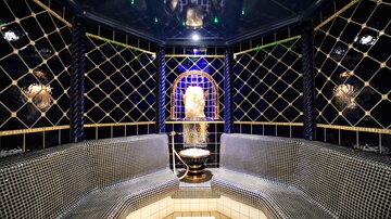 Ein eleganter Raum mit Mosaikwänden und einer zentralen Fontäne. Die entspannende Atmosphäre wird durch sanftes Licht und hochwertige Materialien unterstrichen.