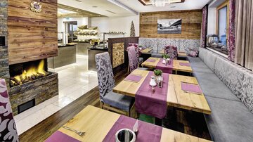 Ein modernes Restaurant mit gemütlicher Einrichtung und einem offenen Kamin. Die Tische sind elegant dekoriert und laden zum Essen ein.