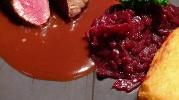 Ein Teller mit rosa gebratenem Fleisch, umgeben von einer braunen Soße. Dazu gibt es Brokkoli, rote Beete und Kartoffelklöße.