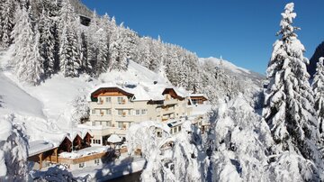 Ein malerisches Bergdorf im Schnee mit verschneiten Bäumen. Die klare blaue Himmel macht die winterliche Szene besonders einladend.