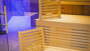 Eine moderne Sauna mit hellen Holzbänken und entspannender Beleuchtung. Der Bereich wirkt sauber und einladend.