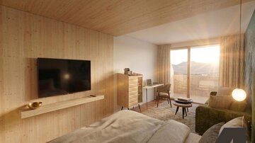 Ein modernes Zimmer mit Holzverkleidung und großen Fenstern. Der Raum ist hell und einladend, mit einem Fernseher, einem Schreibtisch und einer gemütlichen Sitzecke.