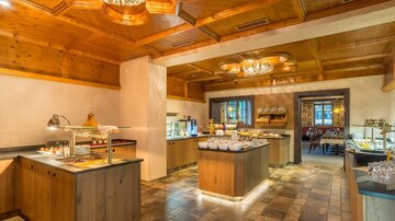 Ein eleganter Speisesaal mit einem Buffet und warmem Holzdekor. Helle Beleuchtung sorgt für eine einladende Atmosphäre.