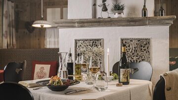 Ein elegant gedeckter Tisch in einem gemütlichen Restaurant. Auf dem Tisch sind Speisen, Weine und Kerzen dekoriert.