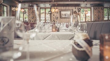 Ein gemütliches Restaurant mit schön gedeckten Tischen und sanfter Beleuchtung. Große Fenster bieten einen Blick nach draußen und schaffen eine einladende Atmosphäre.