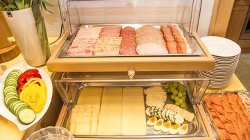 Ein Buffet mit verschiedenen Wurst- und Käsesorten, ergänzt durch frisches Obst und Gemüse. Das Arrangement bietet eine bunte Auswahl an leckeren Snacks.