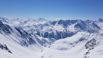 Eine beeindruckende Berglandschaft mit schneebedeckten Gipfeln und klarem blauen Himmel. Die Weite der Alpen strahlt Ruhe und Schönheit aus.
