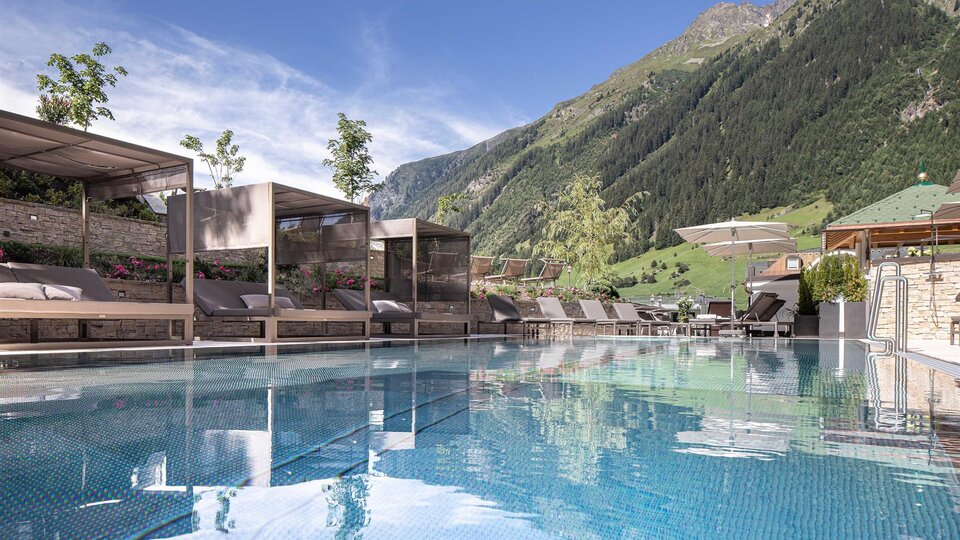 Ein schöner Pool mit Blick auf die Berge und eine klare, blaue Himmel. Liegen und schattige Bereiche laden zum Entspannen ein.