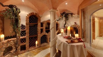 Ein stilvoller Weinkeller mit Weinregalen aus Stein und sanften Kerzenlichtern. Eine elegante Atmosphäre mit einem Tisch für Weinprobe.