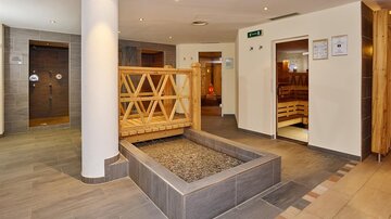 Ein entspannender Wellnessbereich mit Holzsaunen und einem Steinteich. Die moderne Ausstattung und sanften Farben schaffen eine beruhigende Atmosphäre.