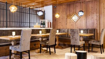 Ein modernes Restaurant mit Holzelementen und gemütlichen Sitzecken. Sanfte Beleuchtung schafft eine einladende Atmosphäre.