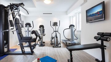 Ein moderner Fitnessraum mit verschiedenen Trainingsgeräten. Der Raum ist hell und einladend gestaltet.