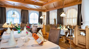 Ein gemütliches Restaurant mit beigen Tischen und eleganter Dekoration. Große Fenster lassen viel Licht herein und schaffen eine einladende Atmosphäre.
