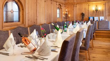 Ein eleganter Essbereich mit Holzvertäfelung und festlich gedeckten Tischen. Die Tische sind mit Gläsern, Besteck und Weinflaschen dekoriert.