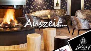 Ein gemütlicher Innenraum mit einem Kamin, der eine entspannende Atmosphäre schafft. Stilvolle Möbel und Holzstämme ergänzen das moderne Design.