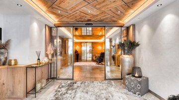 A modern reception area with wooden paneling and an inviting atmosphere. Large windows and decorative plants create a warm ambiance.