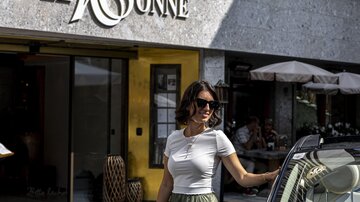 A woman in sunglasses stands next to an elegant car in front of the Hotel Sonne. The building has a modern facade and an inviting atmosphere.