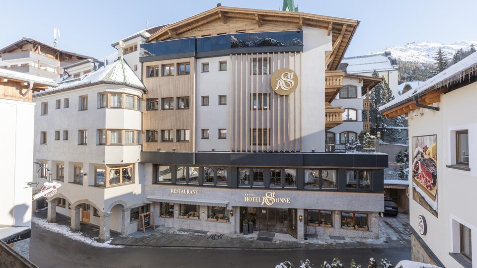 A modern hotel building in a snowy environment. The sky is clear, and the architecture features a mix of traditional and contemporary design.